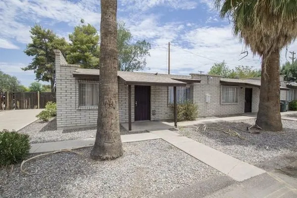a front view of a house with garden and trees