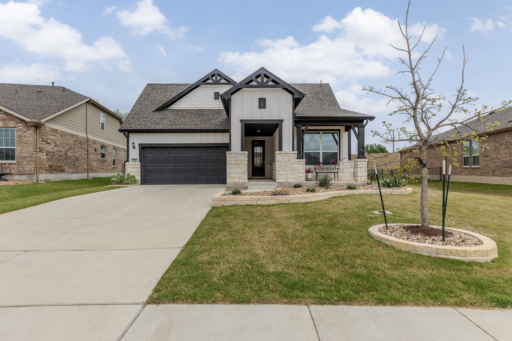 A view of the front of the house with added landscape borders and idylic front porch. 
