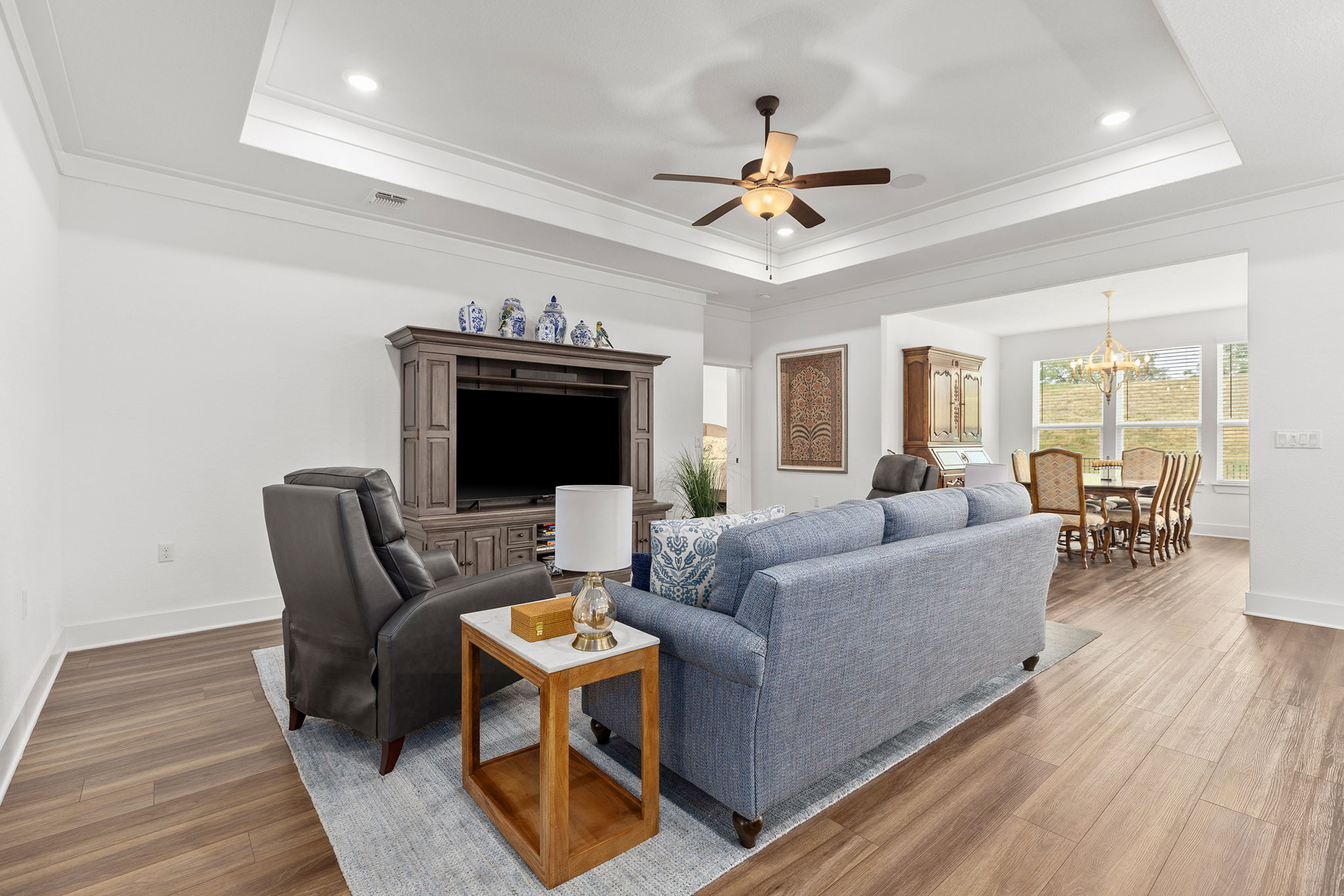 640 Martingale Street Georgetown, TX 78633 - Photo 27 of 39 Living room featuring wood finished floors, ceiling fan, crown molding, hanging lights, and a raised ceiling