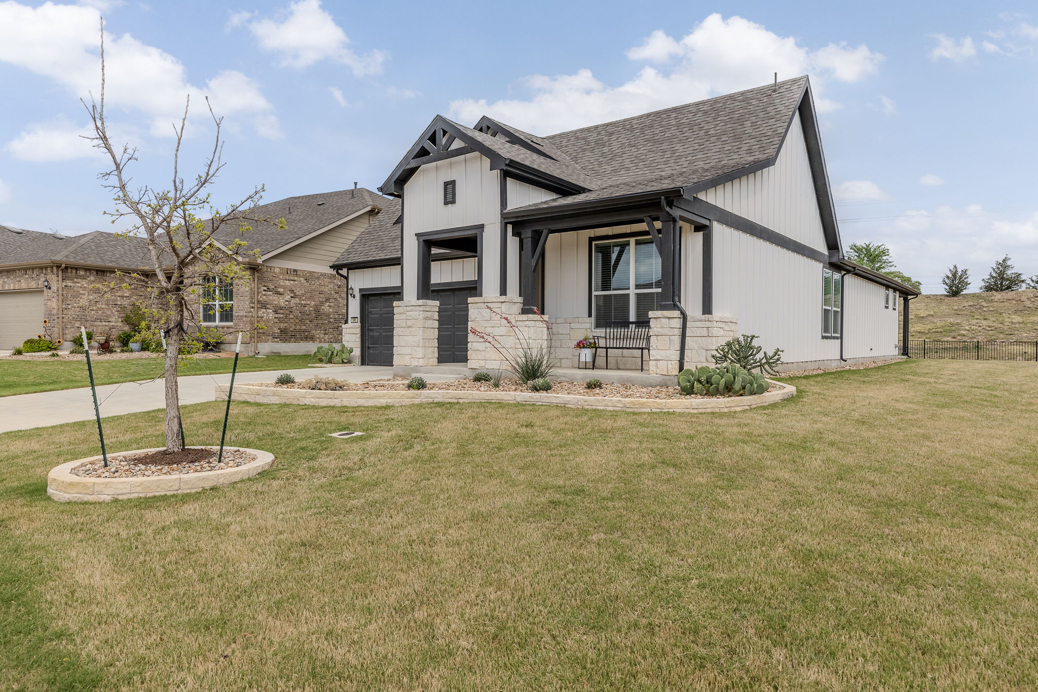 640 Martingale Street Georgetown, TX 78633 - Photo 3 of 39 Modern farmhouse with covered porch, a front lawn, a shingled roof, concrete driveway, and stone siding