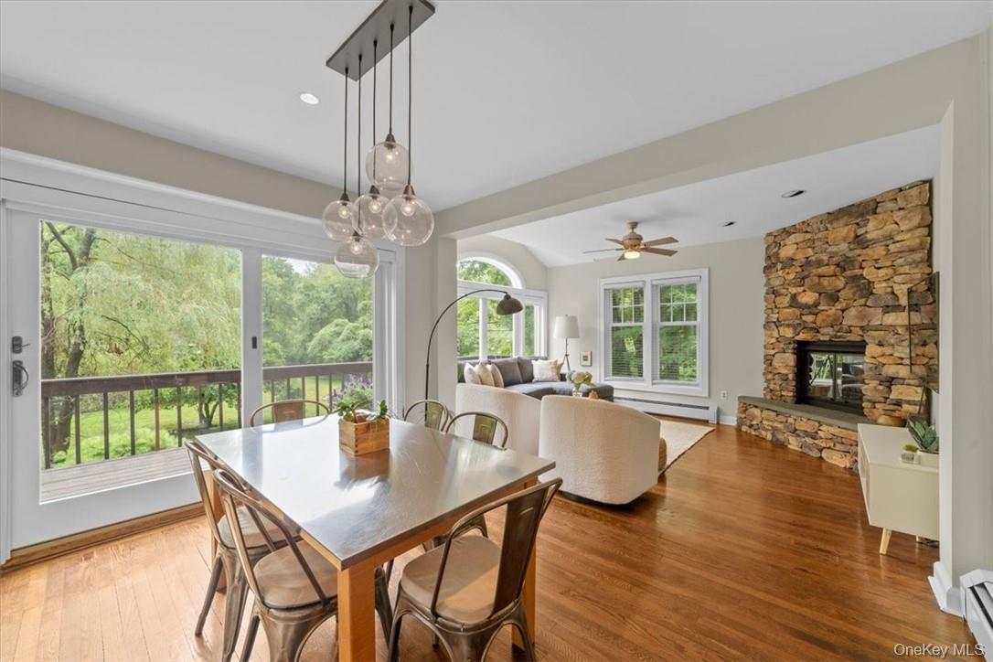 28 Inningwood Road Ossining, NY 10562 - Photo 13 of 37 Dining space with hardwood / wood-style flooring, a baseboard heating unit, ceiling fan with notable chandelier, and a stone fireplace