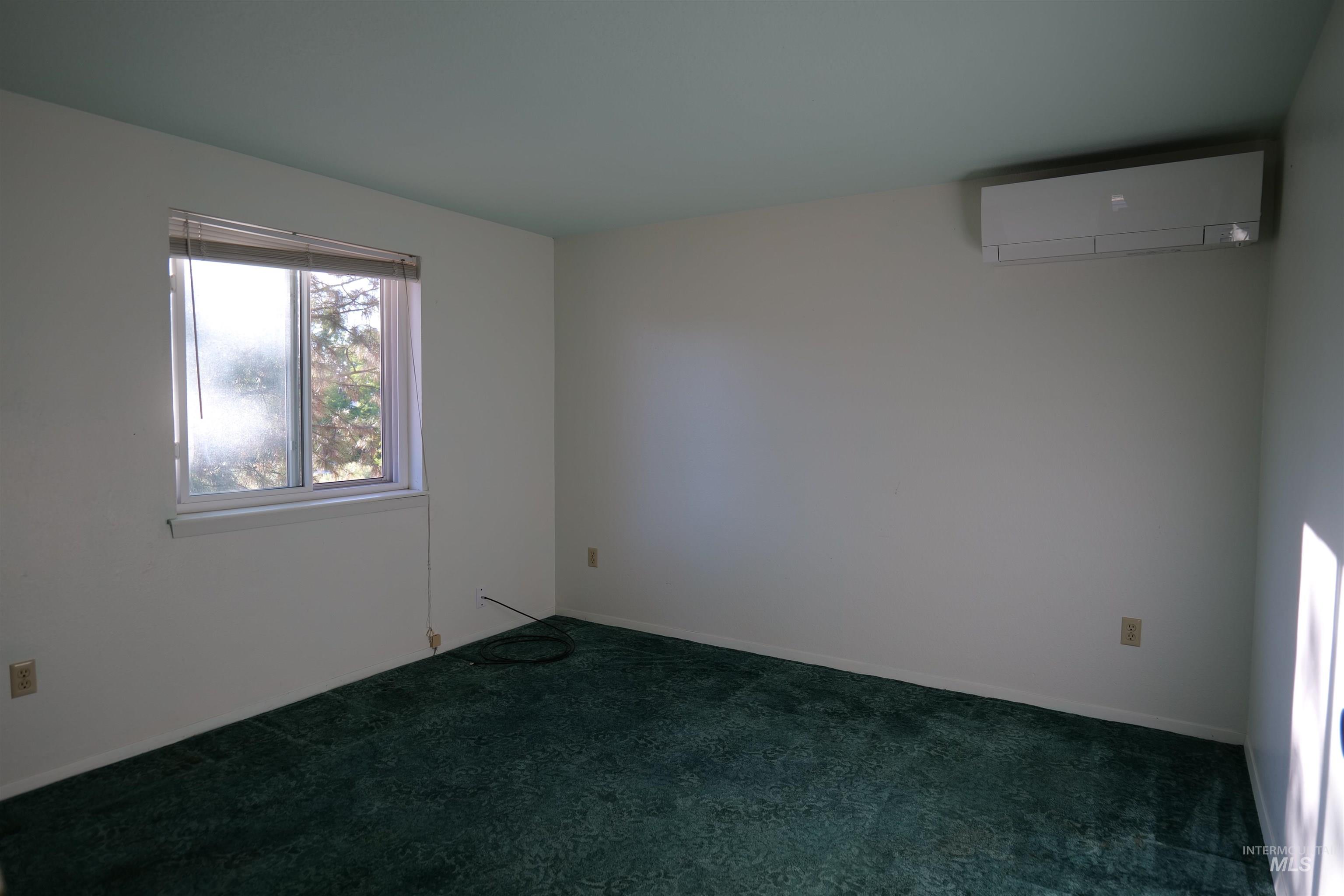 1485 East 9th Street Weiser, ID 83672 - Photo 6 of 18 Room featuring a wall-mounted mini-split system, a window, wall-to-wall carpeting, and white walls