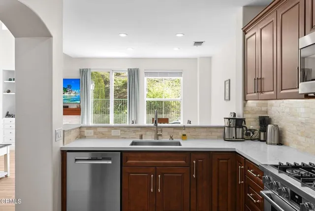 a kitchen with stainless steel appliances granite countertop a sink a window and cabinets