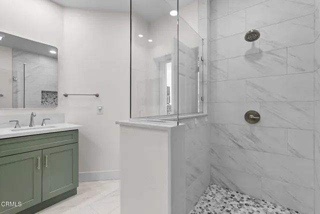 a bathroom with a granite countertop sink a mirror and shower
