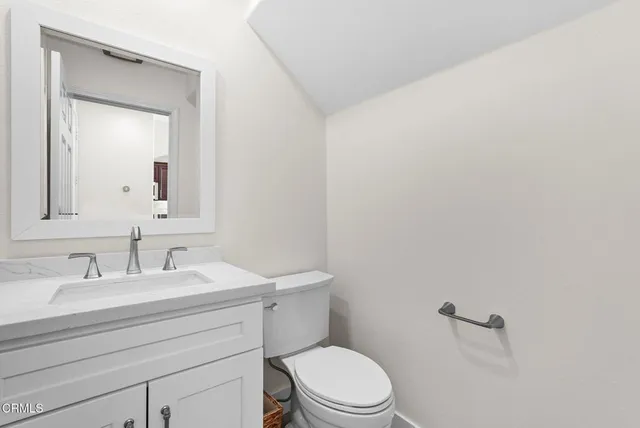 a bathroom with a toilet a sink a mirror and vanity