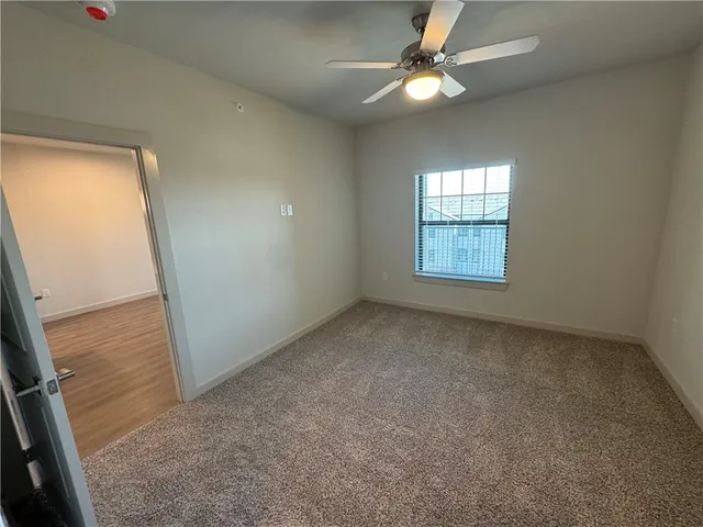 an empty room with windows and chandelier fan