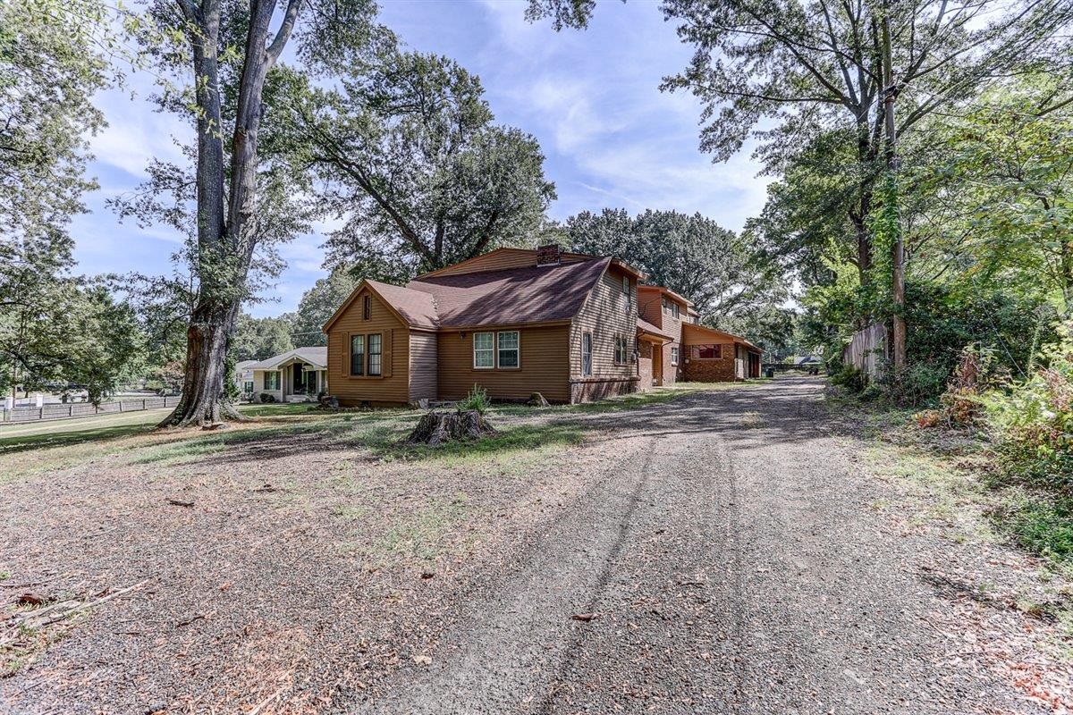 View of property exterior featuring driveway and a chimney