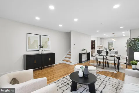a living room with furniture a wooden floor and kitchen view