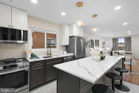 a kitchen with stainless steel appliances a stove a sink a microwave a refrigerator and cabinets