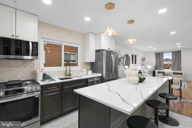 a kitchen with stainless steel appliances a stove a sink a microwave a refrigerator and cabinets