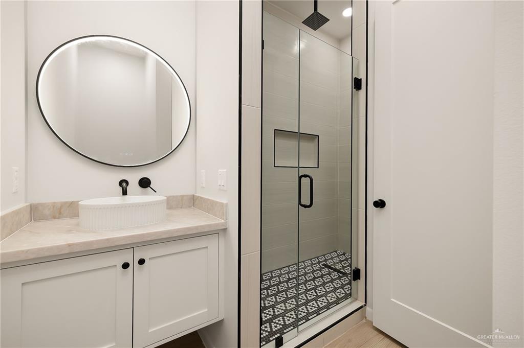 1107 Benjamin Street Mission, TX 78573 - Photo 16 of 19 Modern bathroom featuring a glass-enclosed shower with a patterned tile floor and a built-in niche