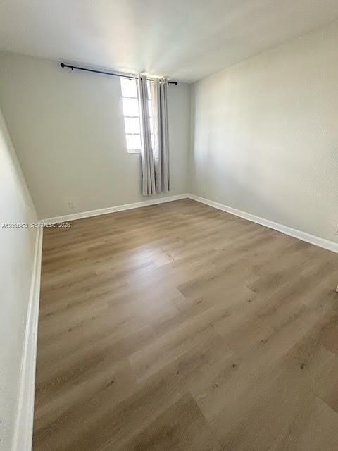 4550 Northwest 9th Street, Unit 803E Miami, FL 33126 - Photo 14 of 31 an empty room with wooden floor and windows with curtains