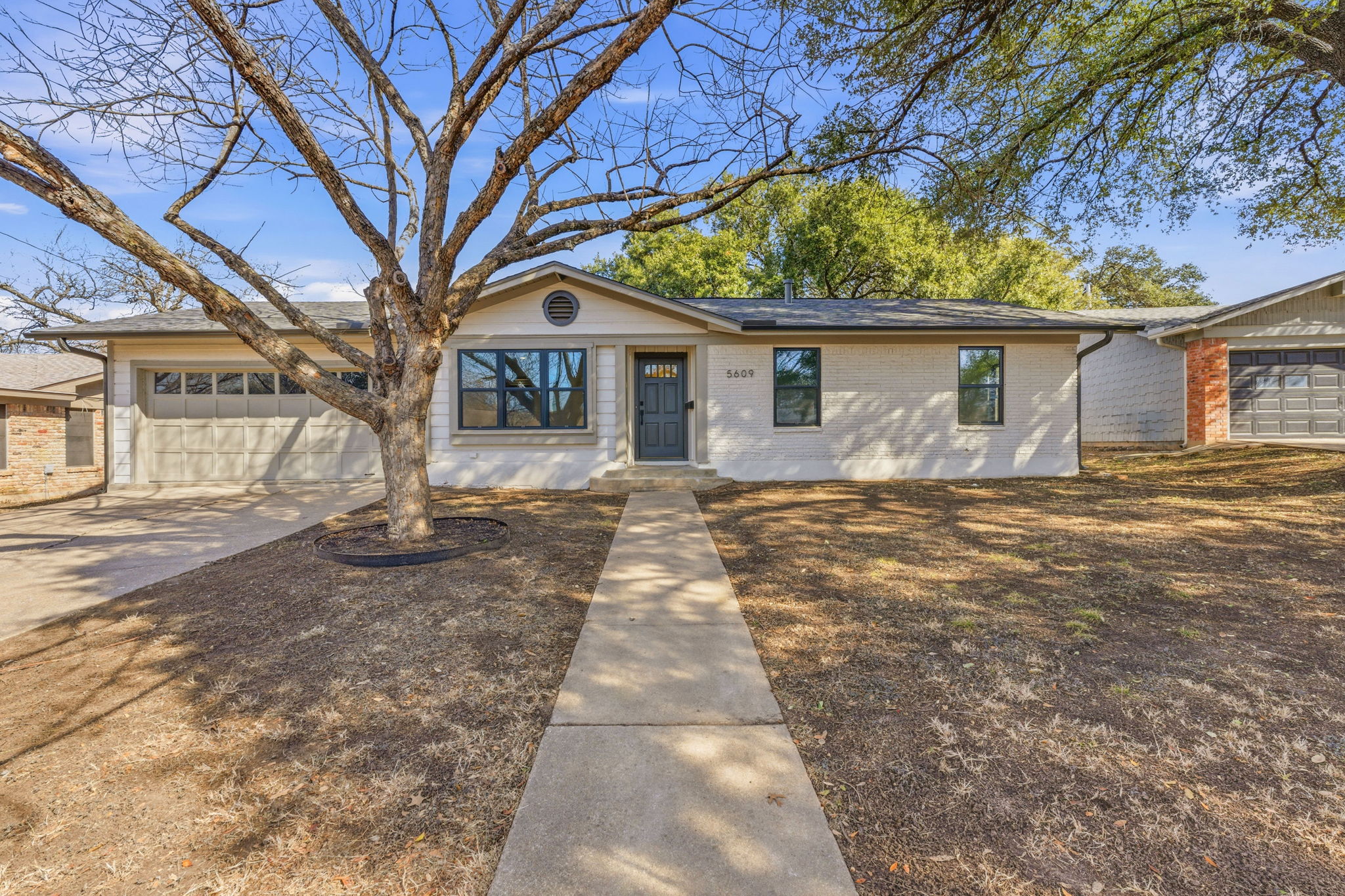 5609 Mapleleaf Drive Austin, TX 78723 - Photo 1 of 19 Ranch-style house featuring brick siding, driveway, and an attached garage