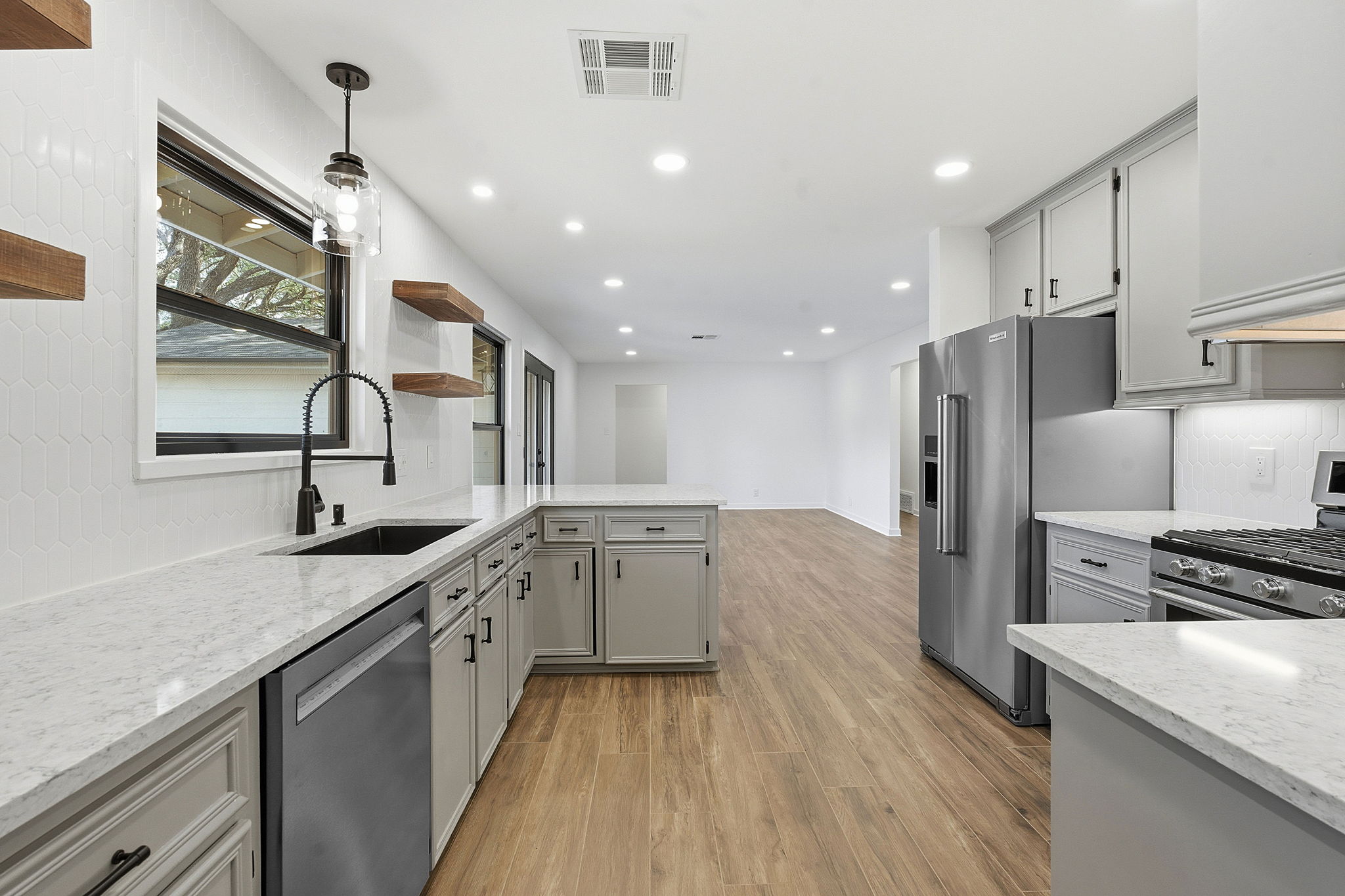 5609 Mapleleaf Drive Austin, TX 78723 - Photo 8 of 19 Kitchen with gray cabinets, open shelves, light stone counters, appliances with stainless steel finishes, and light wood-style floors