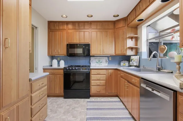 a kitchen with stainless steel appliances granite countertop a stove a sink and a microwave