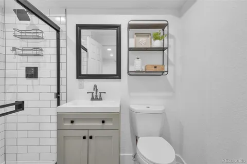 a bathroom with a toilet sink vanity and mirror