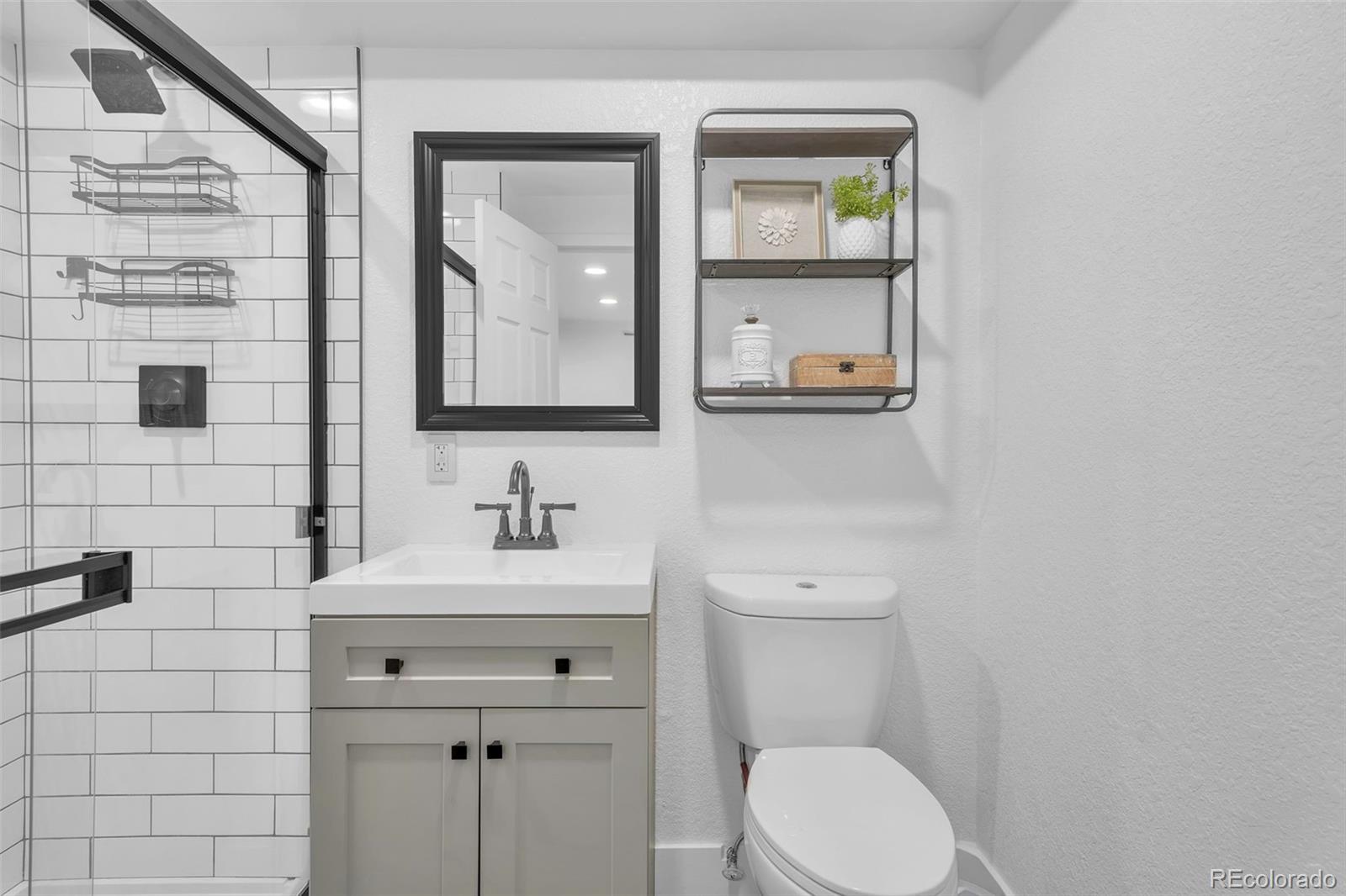 2808 Eaton Street Wheat Ridge, CO 80214 - Photo 16 of 36 a bathroom with a toilet sink vanity and mirror