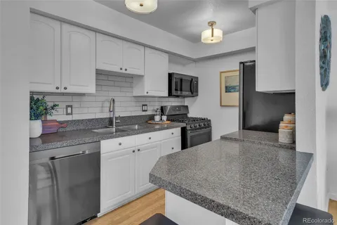 a kitchen with granite countertop a sink stainless steel appliances and cabinets