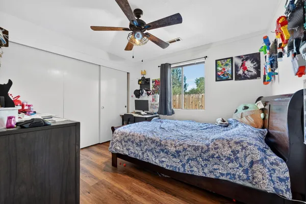 a bedroom with a bed and dresser with wooden floor