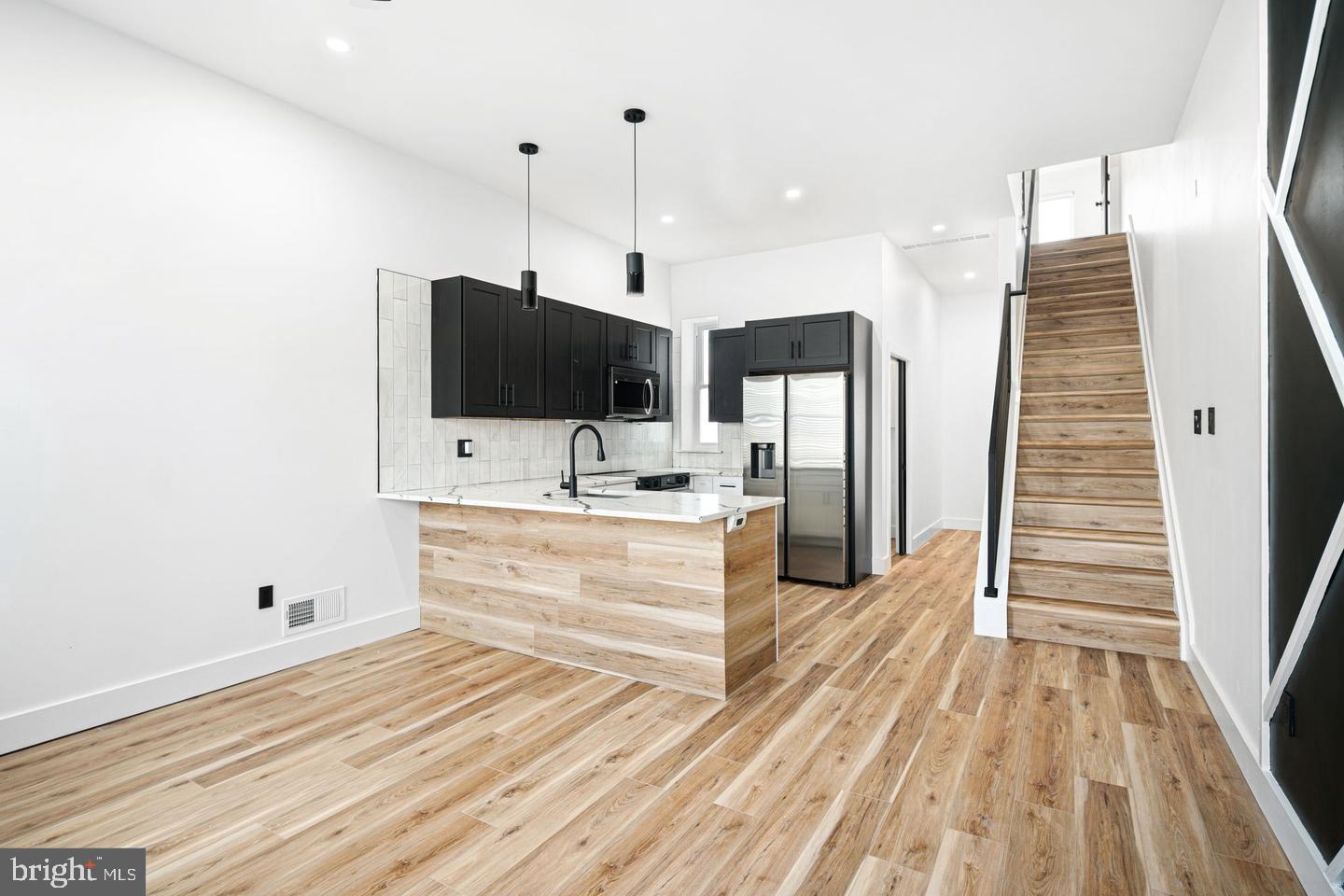 a view of kitchen with stainless steel appliances kitchen island wooden floor and window