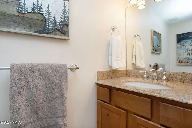 a bathroom with a granite countertop sink a mirror and shower