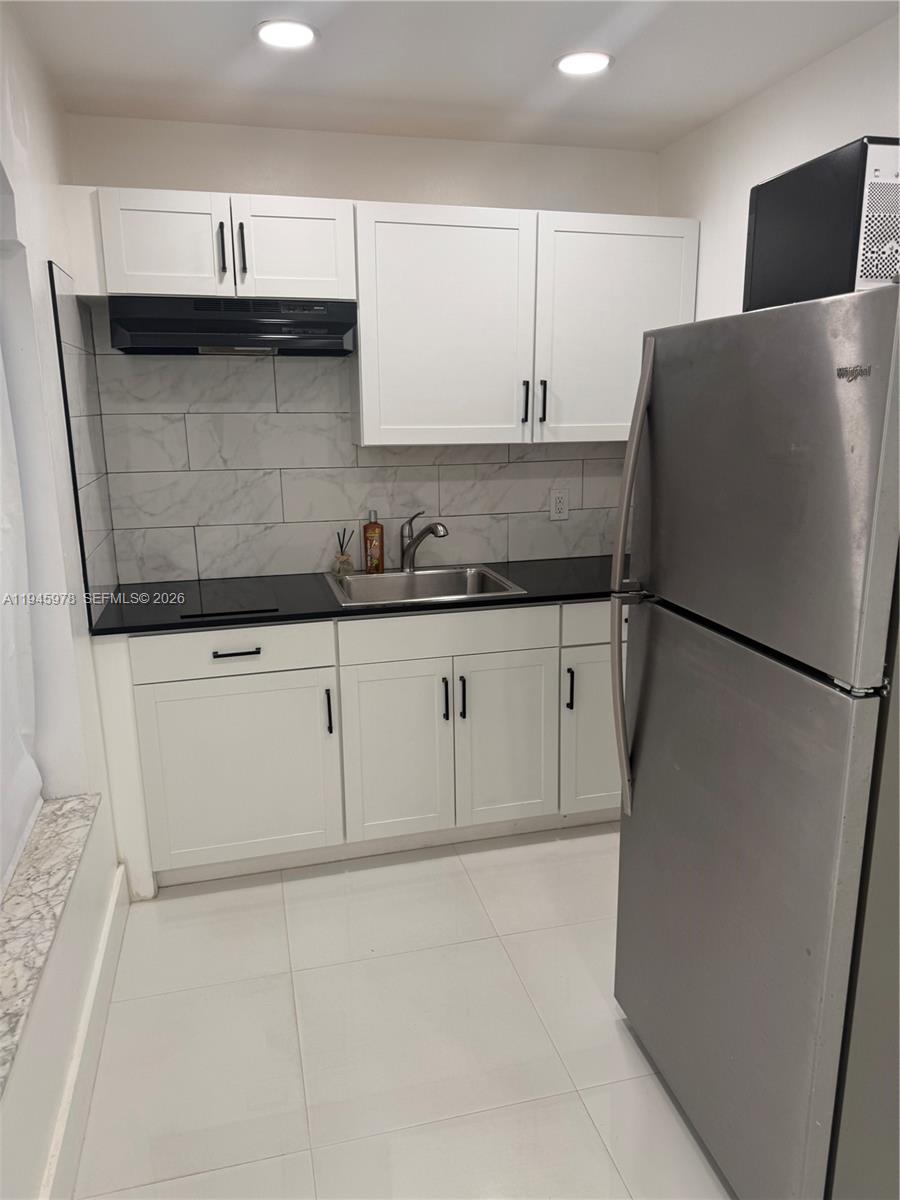 14320 Southwest 147th Court, Unit E1 Miami, FL 33196 - Photo 5 of 8 a kitchen with granite countertop a refrigerator and a sink