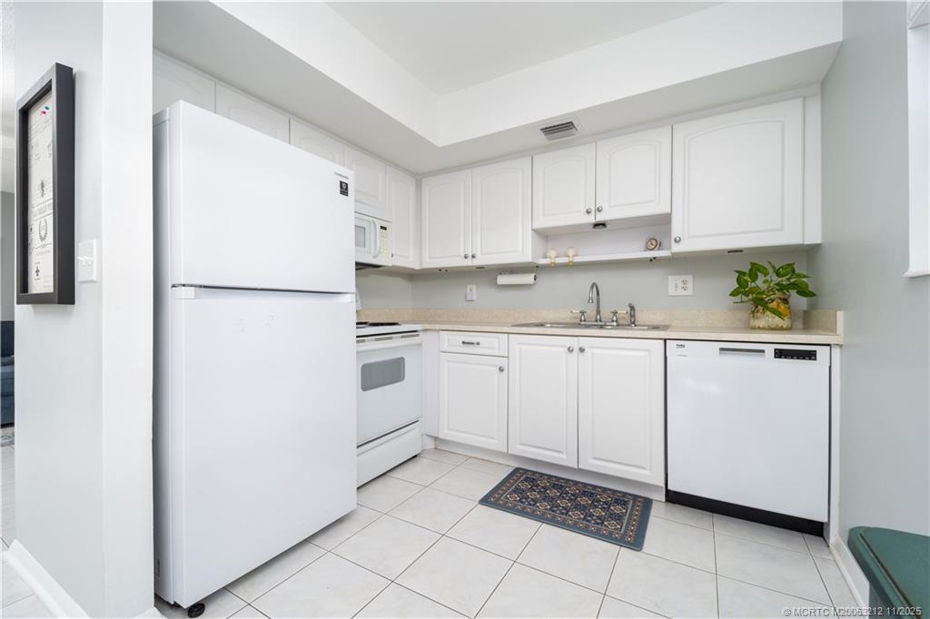2929 Southeast Ocean Boulevard, Unit K1 Stuart, FL 34996 - Photo 6 of 26 a kitchen with white cabinets and white appliances