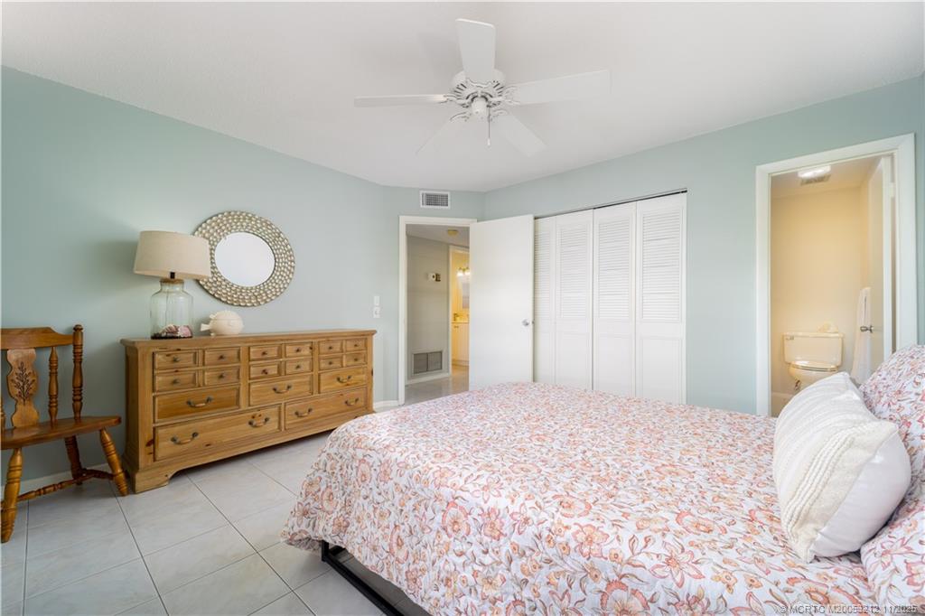 2929 Southeast Ocean Boulevard, Unit K1 Stuart, FL 34996 - Photo 8 of 26 a bedroom with a bed a dresser and a chandelier
