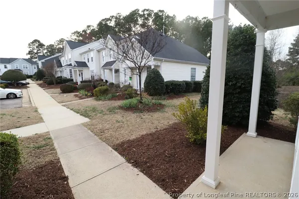 a view of a white house next to a yard with potted plants