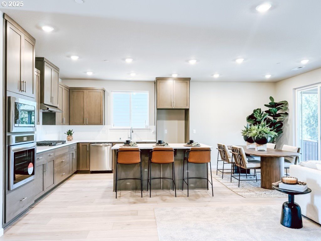 2607 South 6th Way Ridgefield, WA 98642 - Photo 21 of 32 a kitchen with stainless steel appliances kitchen island granite countertop a table chairs sink and cabinets