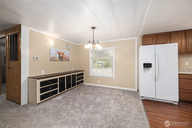 a kitchen with granite countertop a refrigerator a sink dishwasher a stove top oven a dining table and chairs with wooden floor