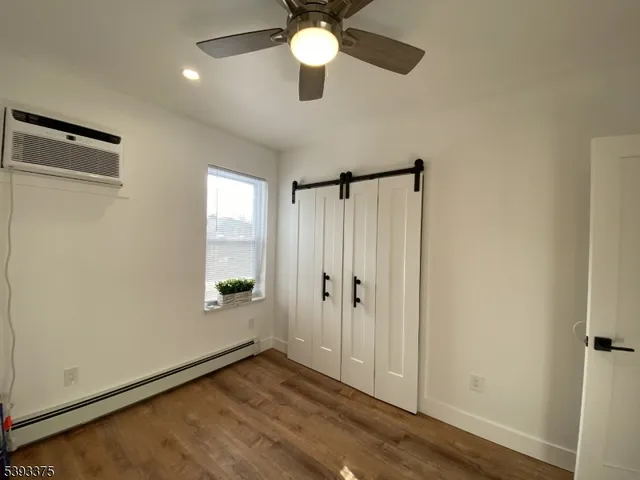 a view of an empty room and window with a ceiling fan