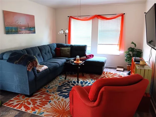 a living room with furniture a flat screen tv and a window