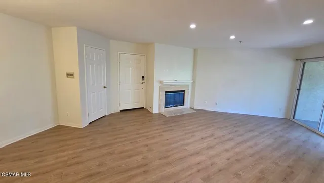 a view of empty room with wooden floor and fireplace