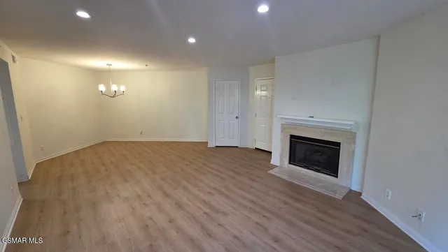 a view of empty room with wooden floor and fireplace