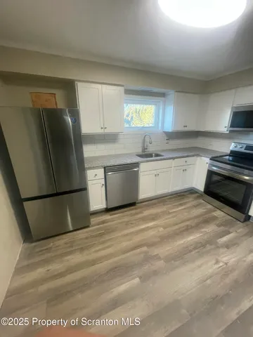 a kitchen with stainless steel appliances granite countertop a sink a stove top oven a counter space and cabinets