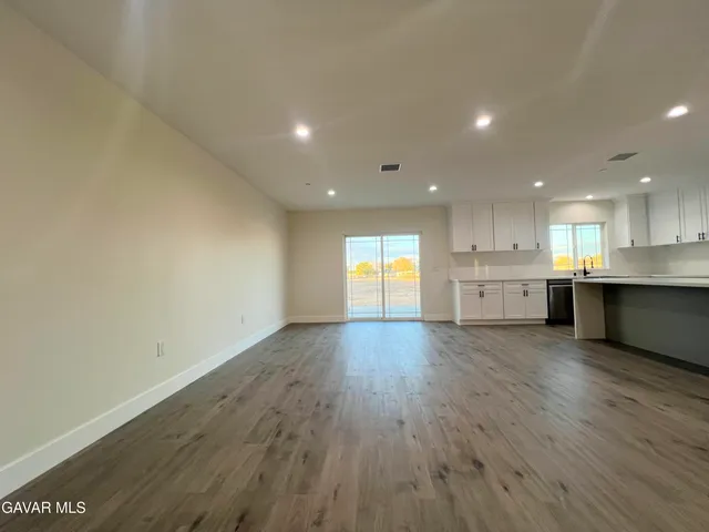 a large kitchen with a large counter top a sink stainless steel appliances and cabinets