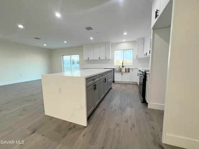 a large white kitchen with kitchen island sink and cabinets