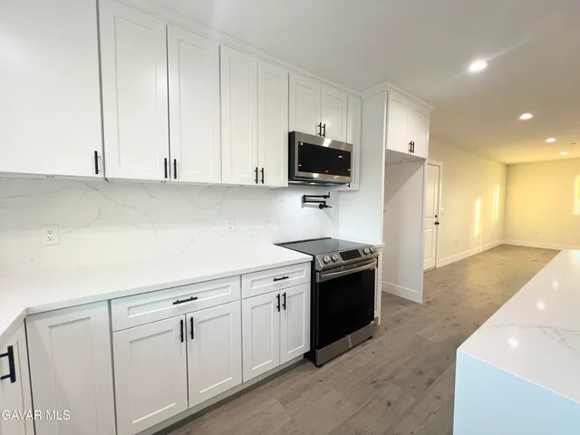 a view of an empty room with wooden floor and a ceiling fan