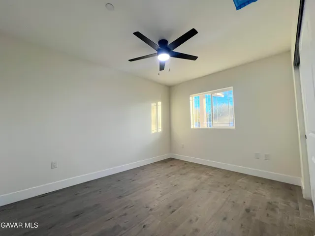 an empty room with wooden floor and a ceiling fan