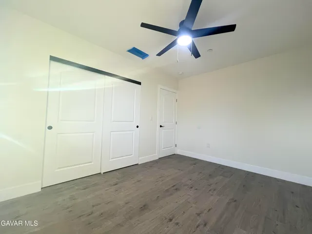 a view of empty room with wooden floor and fan