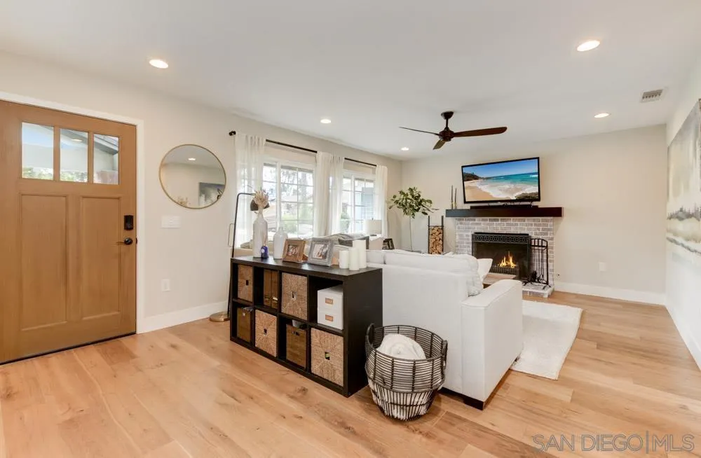 9944 Connell Road San Diego, CA 92131 - Photo 3 of 25 a living room with furniture a fireplace and a open kitchen view