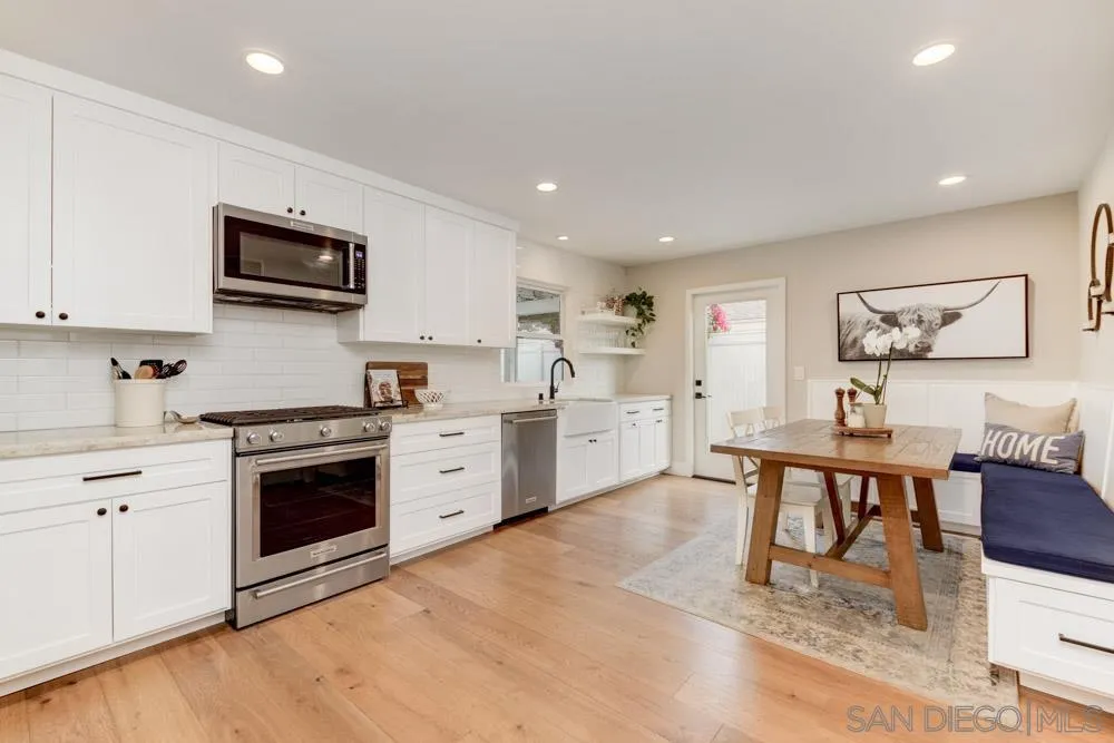 9944 Connell Road San Diego, CA 92131 - Photo 6 of 25 a kitchen with stainless steel appliances kitchen island granite countertop a stove top oven a sink a dining table and chairs with wooden floor