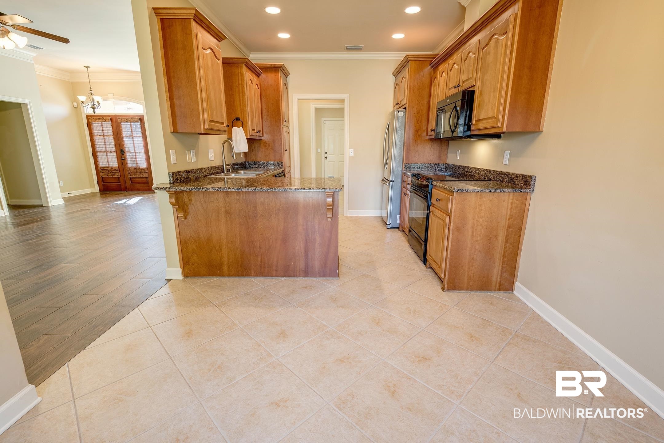9421 Collier Loop Daphne, AL 36526 - Photo 15 of 31 Kitchen with dark stone counters, light tile patterned floors, a peninsula, black appliances, and brown cabinets
