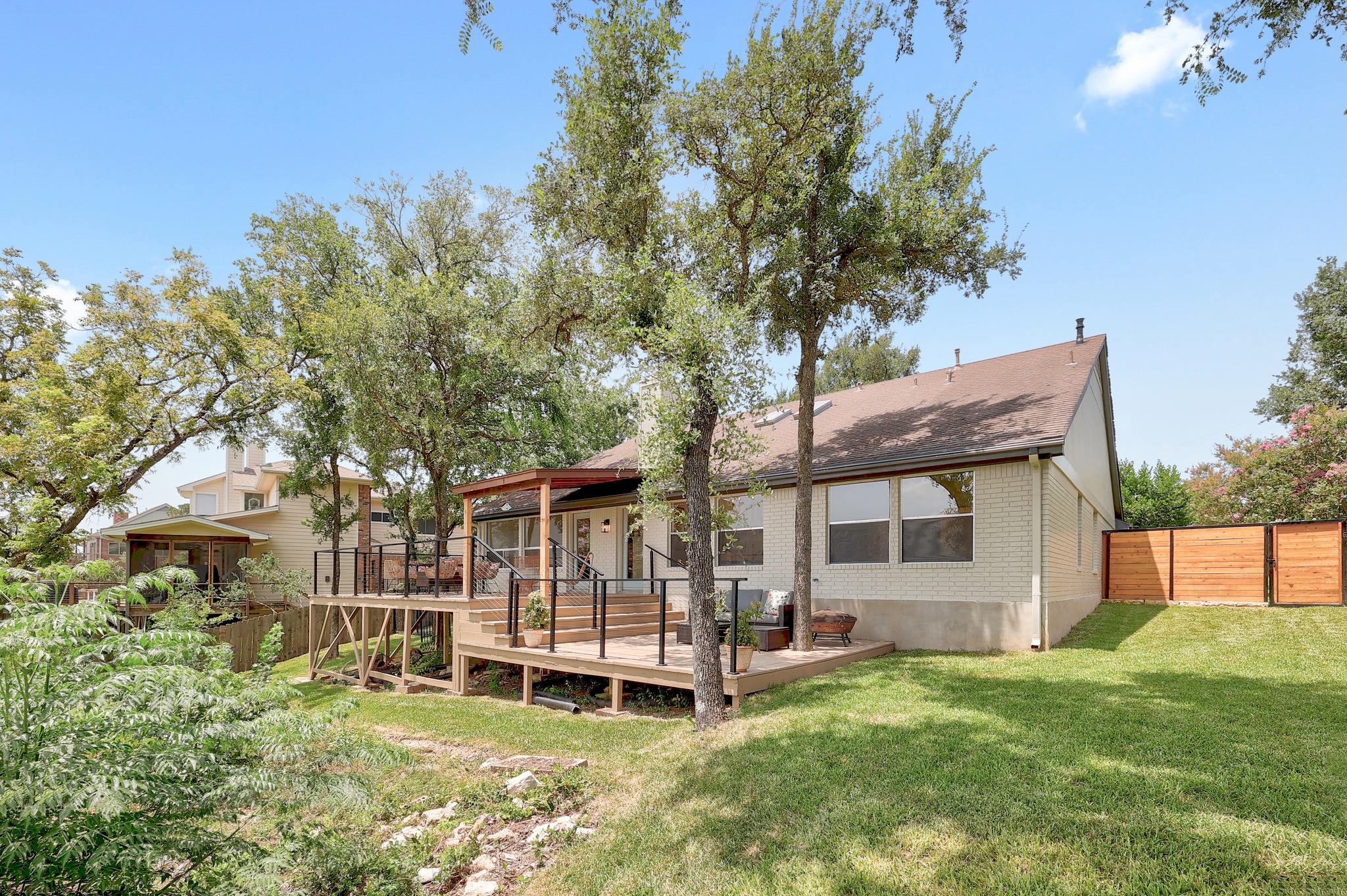 7705 Jester Boulevard Austin, TX 78730 - Photo 26 of 36 A spacious backyard with an elevated wood deck, ideal for gatherings, and a well-maintained lawn.