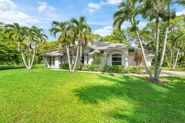 front view of a house with a yard and palm trees