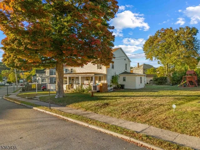a view of a white house with a yard next to a road