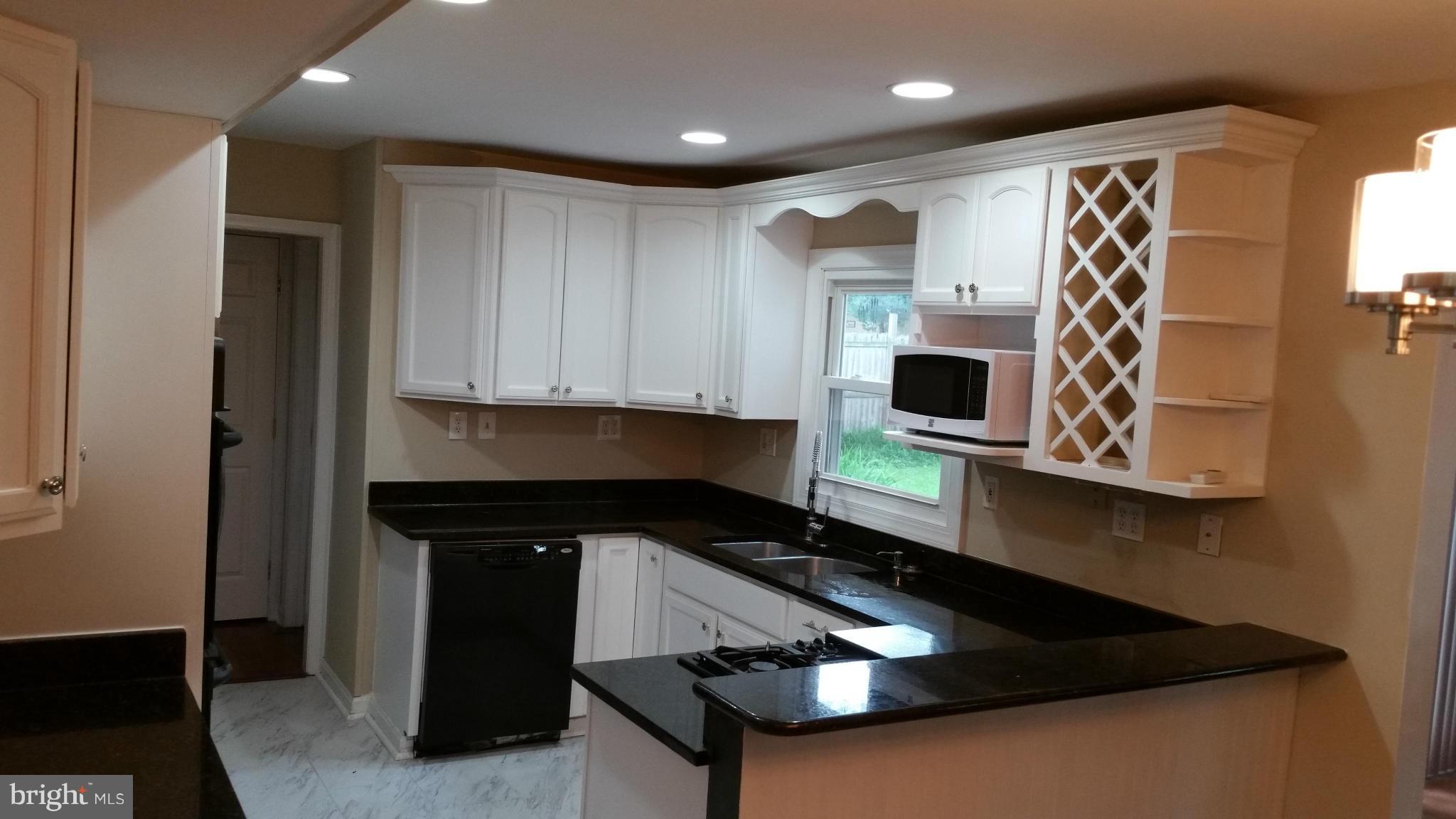 12408 Starlight Lane Bowie, MD 20715 - Photo 13 of 26 a kitchen with stainless steel appliances granite countertop a sink and a stove top oven with wooden floor