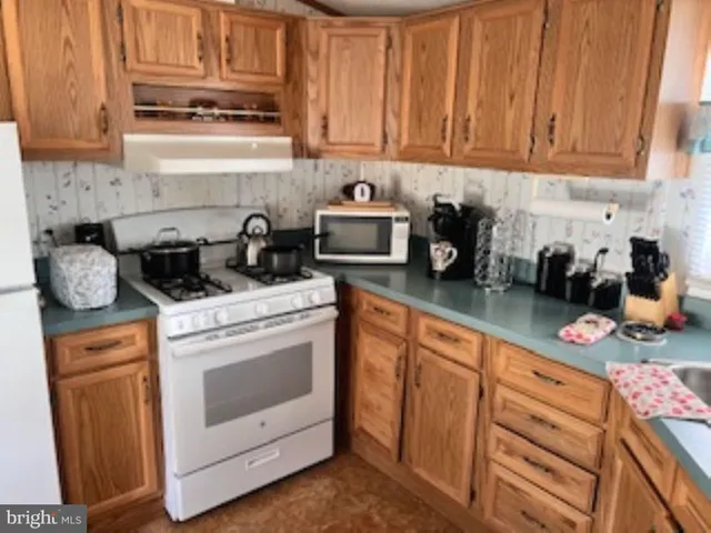 a kitchen with stainless steel appliances granite countertop a stove a sink dishwasher and cabinets with wooden floor