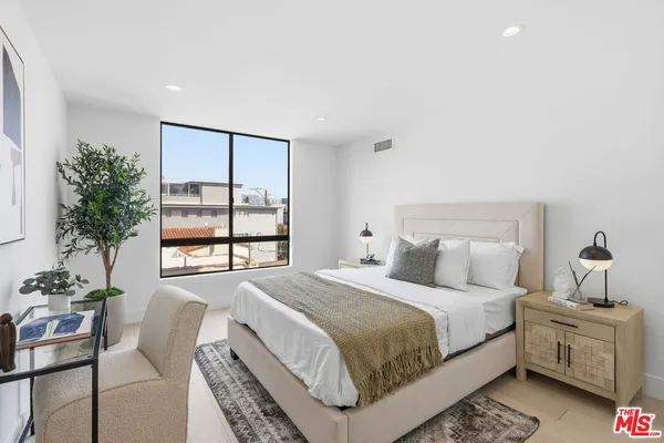 a bedroom with a large bed and a potted plant